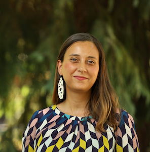 Photo of a white woman with brown hair and colorful top